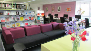 Comfortable seating area showing library journals in the background and a vase of flowers on a table in the foreground